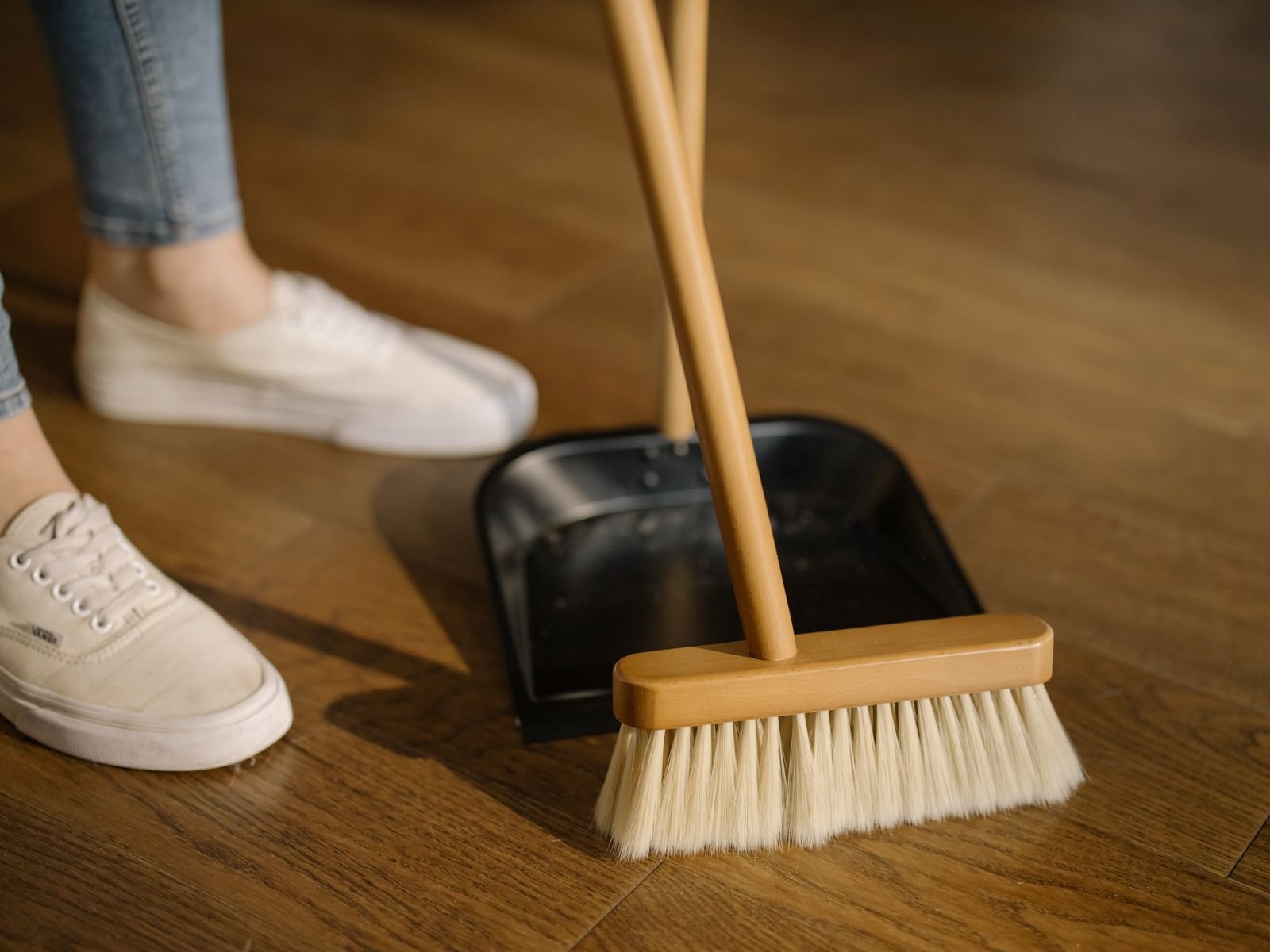 Broom, dustpan and canvas shoes on a wooden floor. This is not the advertised iRobot model.